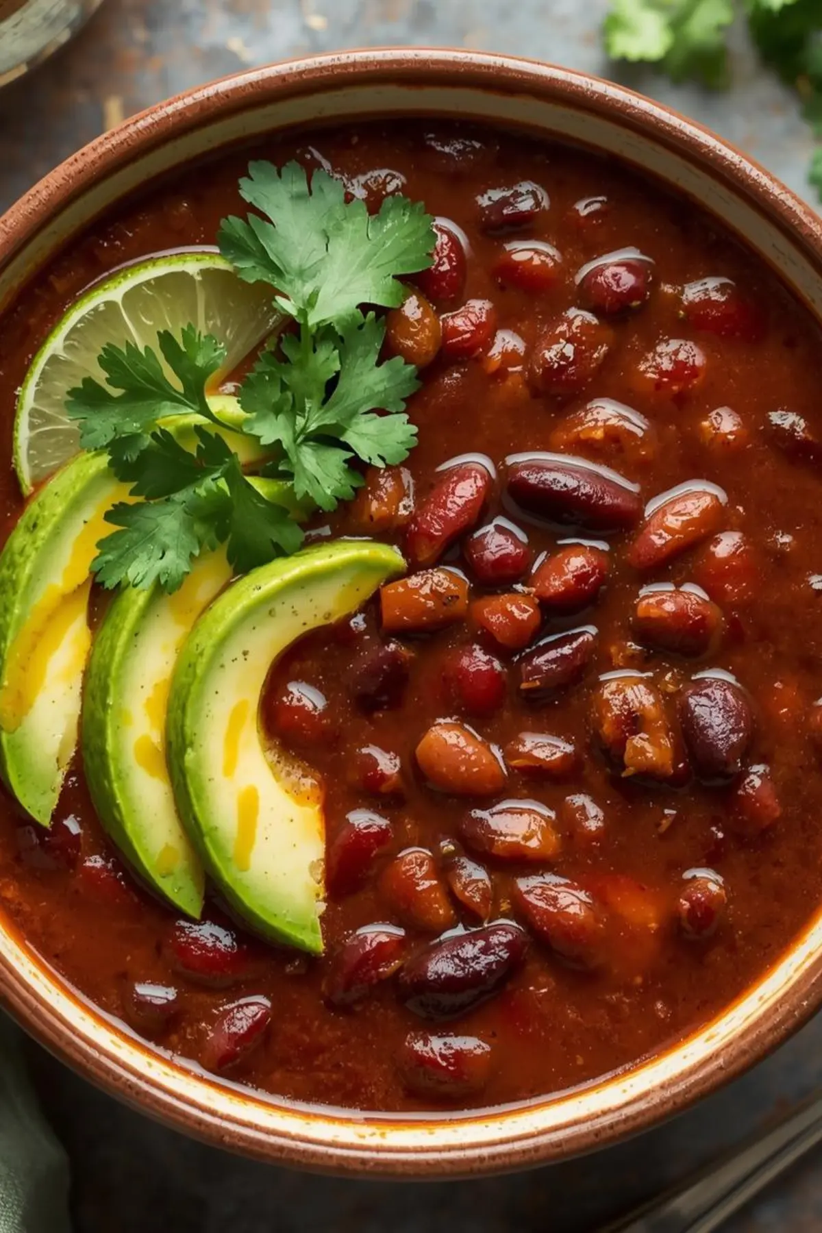 Bowl of smoky black bean soup topped with cilantro, avocado, and lime